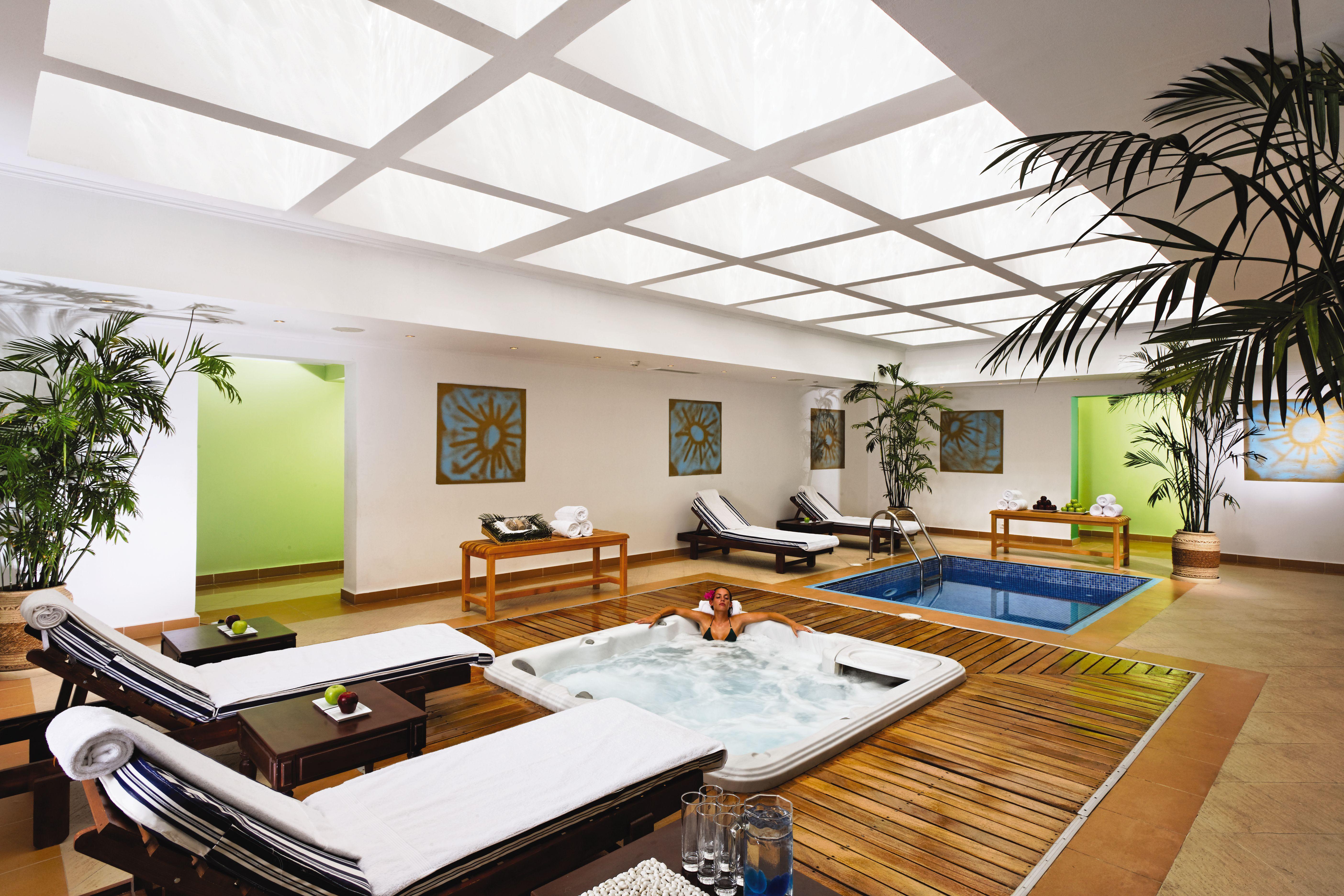 Movenpick Taba Resort & Spa Konforlar fotoğraf The photo shows an indoor spa or relaxation area. It features a small pool and a hot tub, surrounded by wooden decking. There are lounge chairs, likely for relaxation, placed around the space. The walls are painted in soft colors, and there are decor