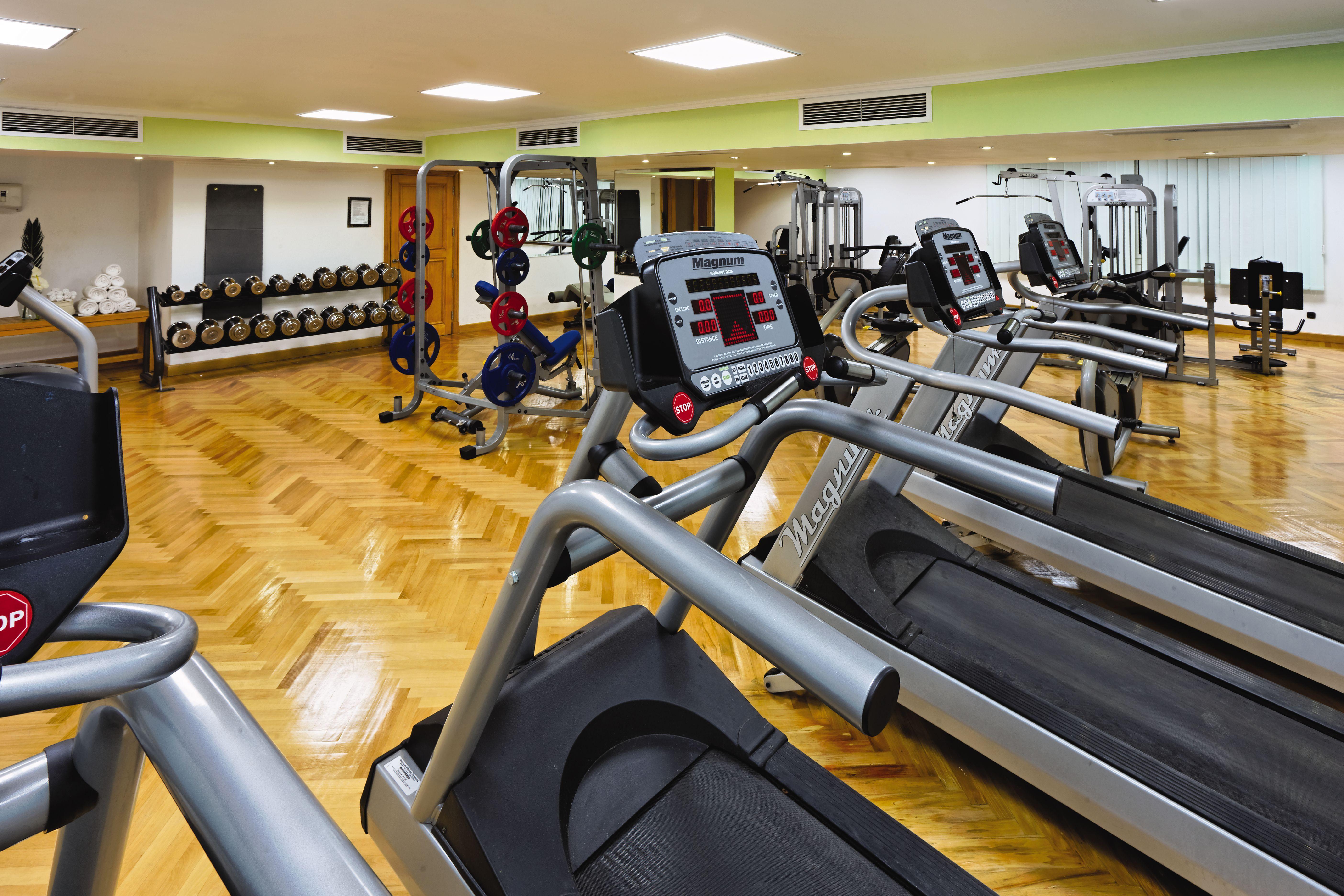 Movenpick Taba Resort & Spa Dış mekan fotoğraf The photo shows a fitness gym equipped with multiple exercise machines. There are several treadmills lined up in a row, each featuring a digital display. In the background, there are weightlifting stations with various dumbbells and weight plates nea