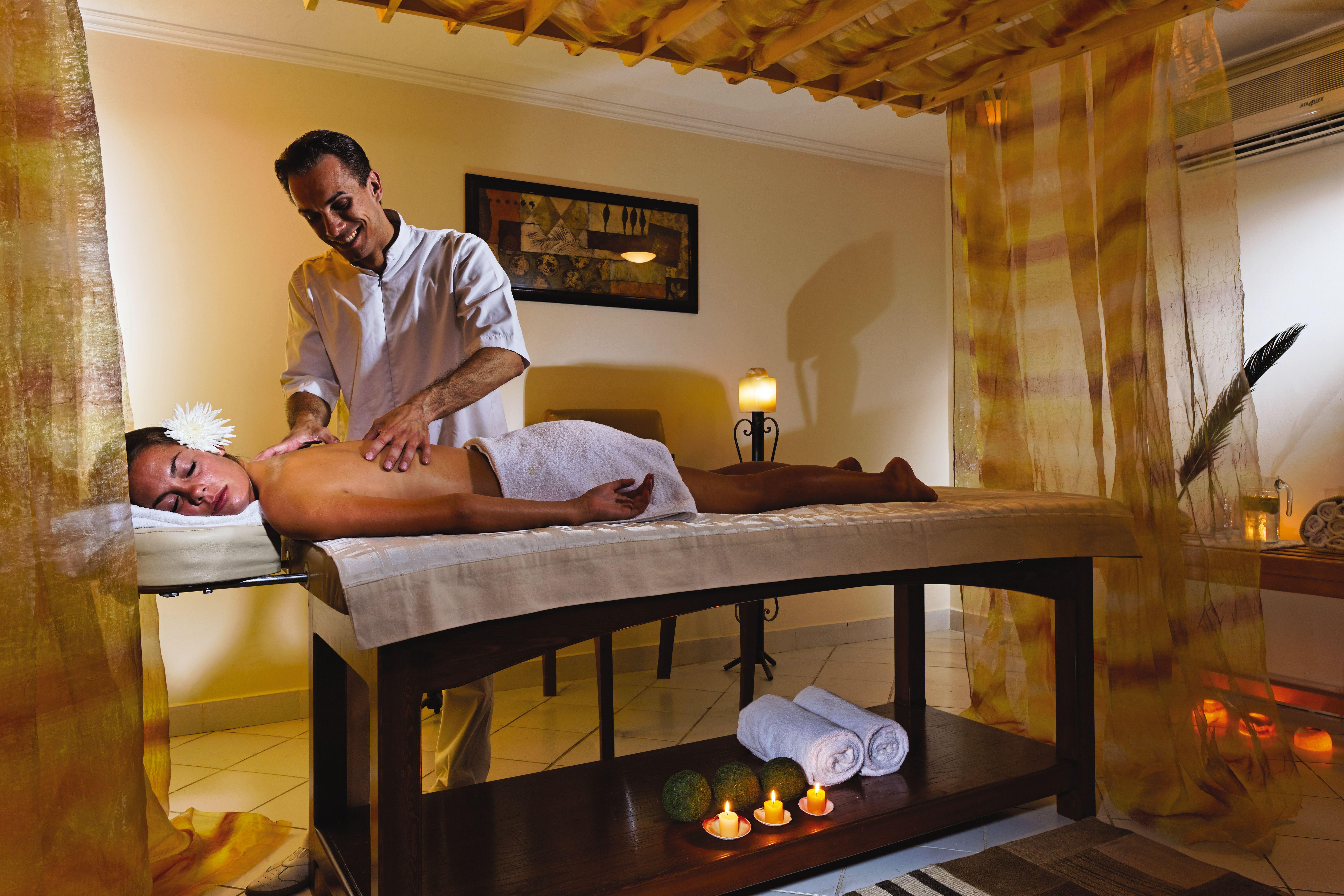 Movenpick Taba Resort & Spa Dış mekan fotoğraf The photo shows a tranquil spa setting where a massage is taking place. A person lies on a massage table, covered with a white towel, while a therapist administers a massage. The room is softly lit and decorated with calming colors. There are candles