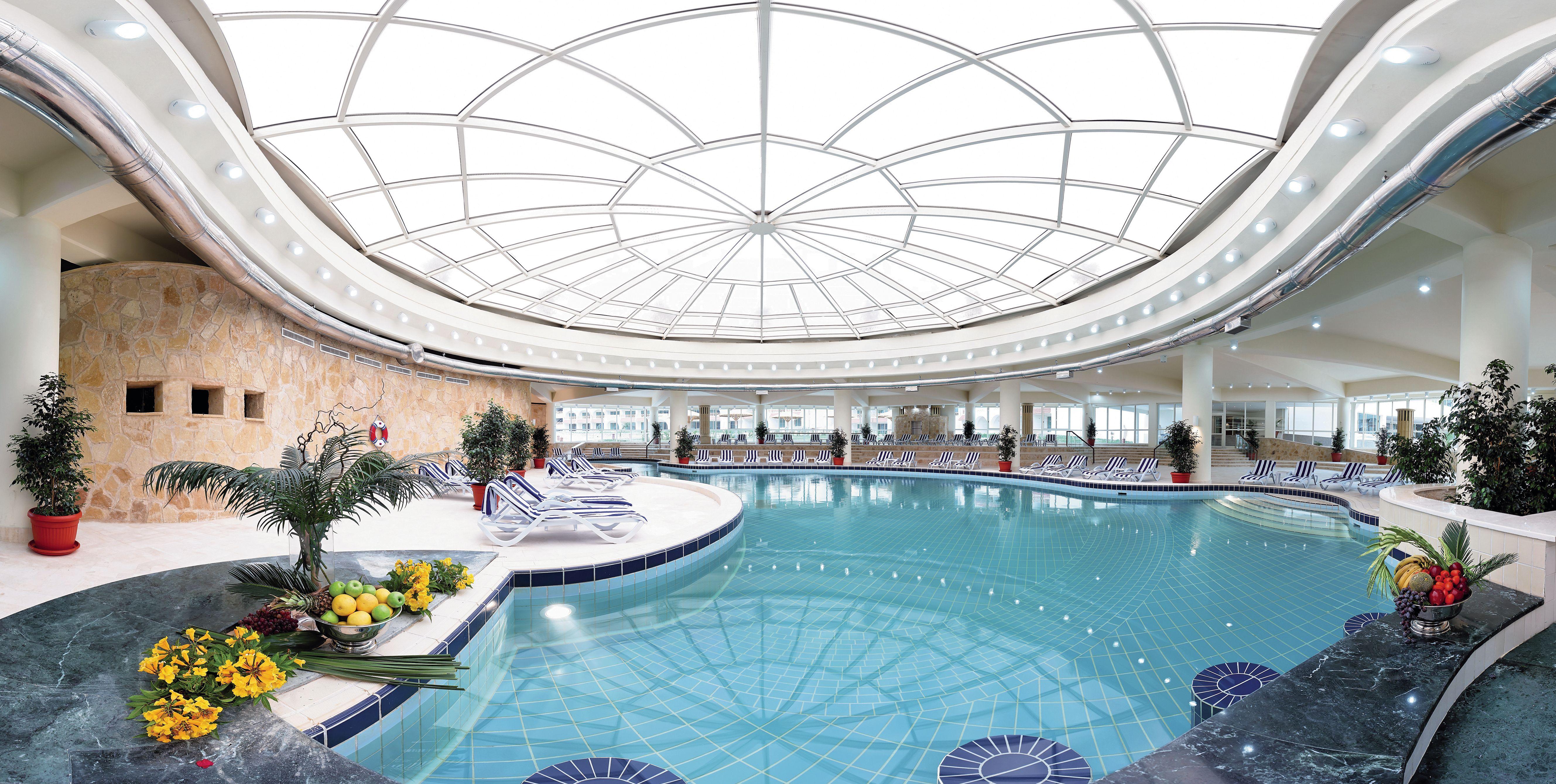 Movenpick Taba Resort & Spa Dış mekan fotoğraf The photo shows an indoor swimming pool area with a spacious and bright design. The pool has a circular shape with a clear blue water surface, surrounded by a tiled edge. The ceiling features a large glass structure, allowing natural light to illumin