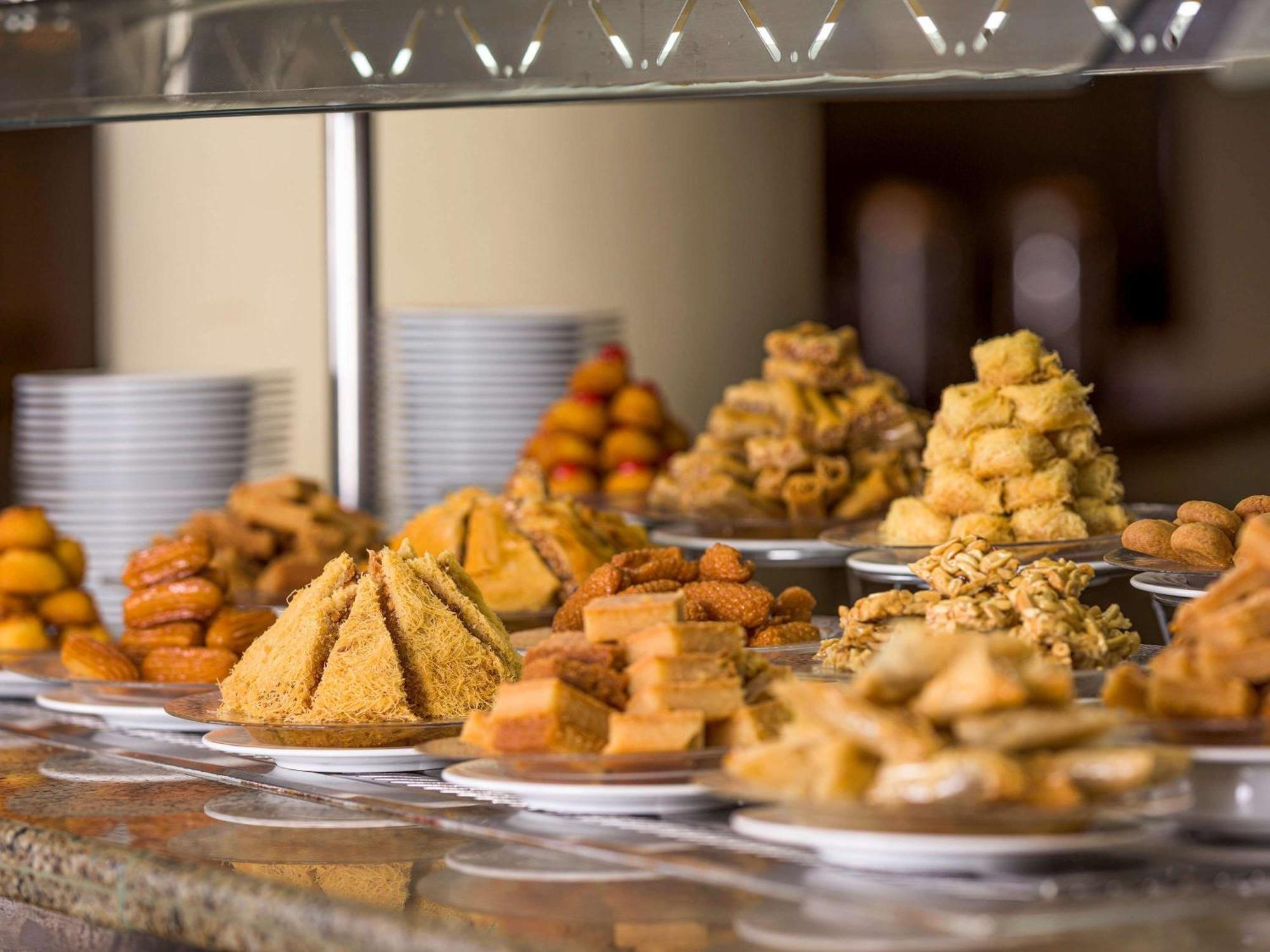 Movenpick Taba Resort & Spa Dış mekan fotoğraf The photo showcases a variety of desserts displayed on a table. There are several types of sweet treats, including pastries and confections. Some are arranged in pyramid shapes, while others are in neat piles or on small plates. The desserts appear t