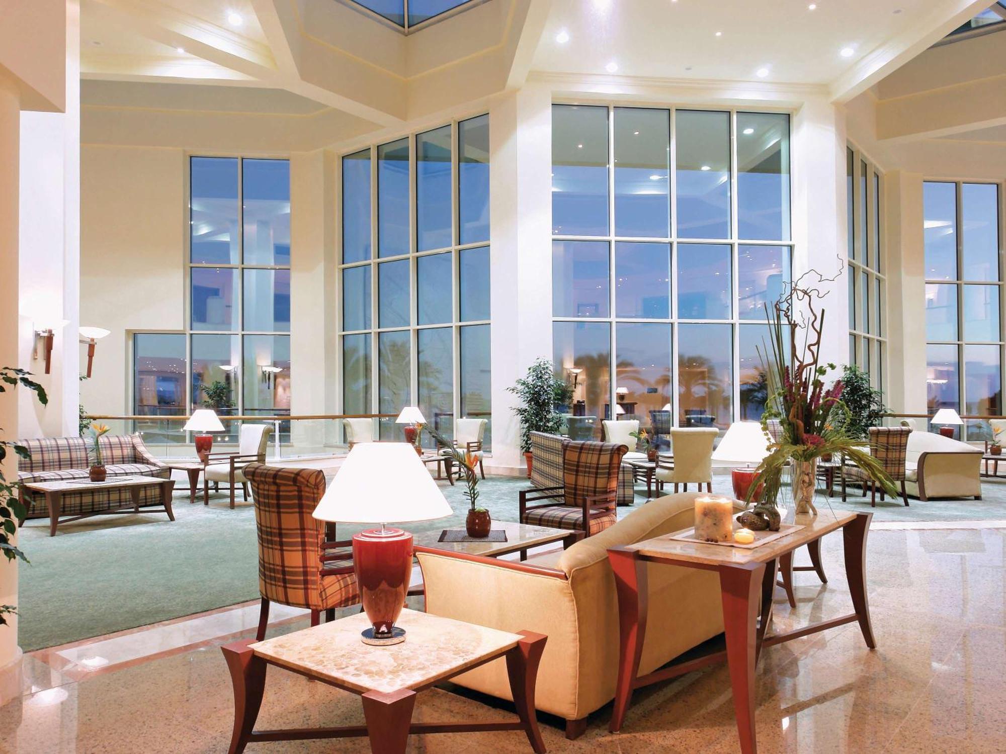 Movenpick Taba Resort & Spa Dış mekan fotoğraf The photo shows a spacious and elegantly designed lobby area. It features large windows that allow natural light to flood the space, creating a bright atmosphere. The lobby is furnished with comfortable seating arrangements, including sofas and armch